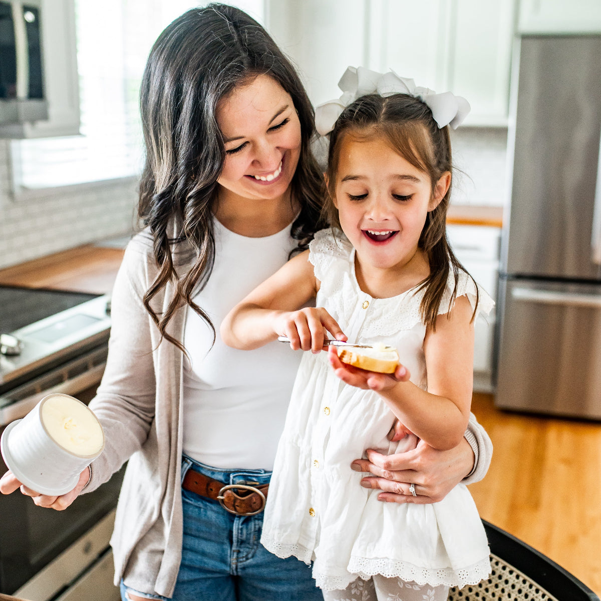Woman and child in a kitchen using butter crock to spread soft butter on bread